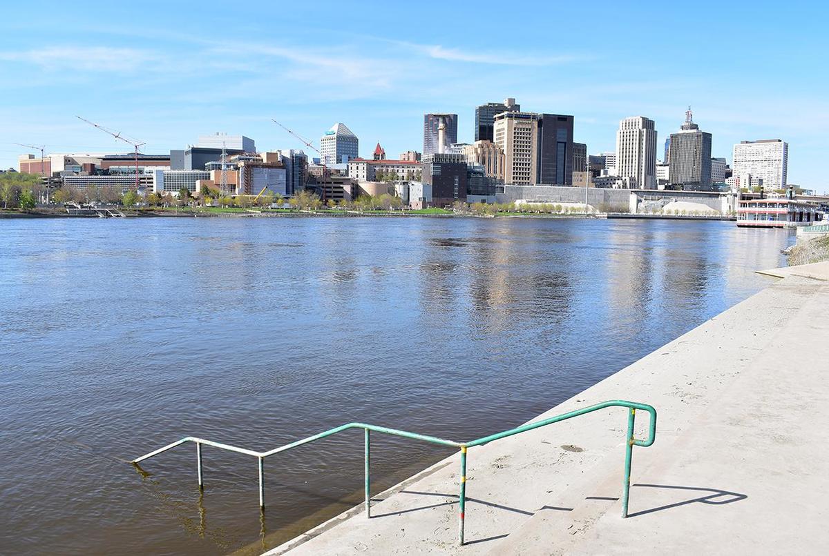 Mississippi River shown in flood just outside of downtown St. Paul, showing steps and a banister partially submerged.
